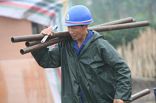 工人冒雨作业建家园